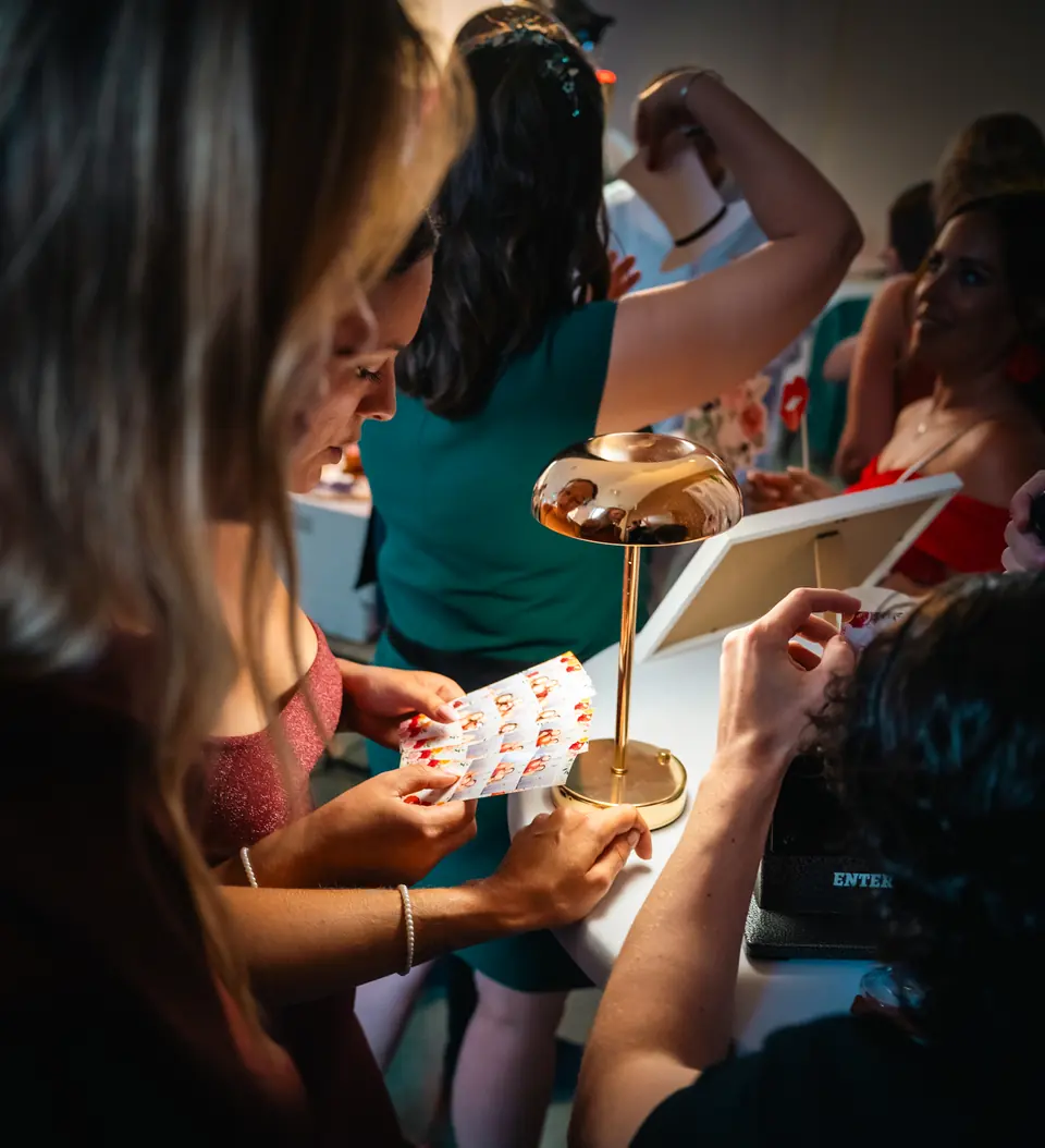 Une invitée tend sa bande photo à l'opérateur, à la table de fabrication des porte-clés.