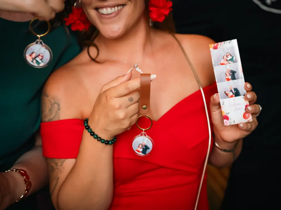 Gros plan sur deux porte-clés terminés, la photo de la soirée sertie dans la médaille, à côté de la bande photo assortie.