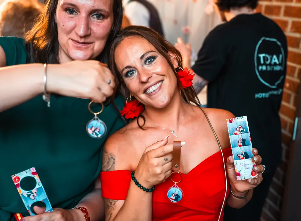 Deux invitées montrent leurs porte-clés et leurs bandes photo à la fin de la soirée.