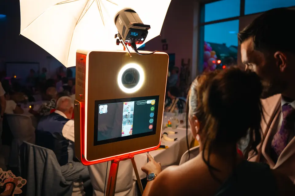 Des invités devant la borne photobooth en bois, au moment de la prise de vue.